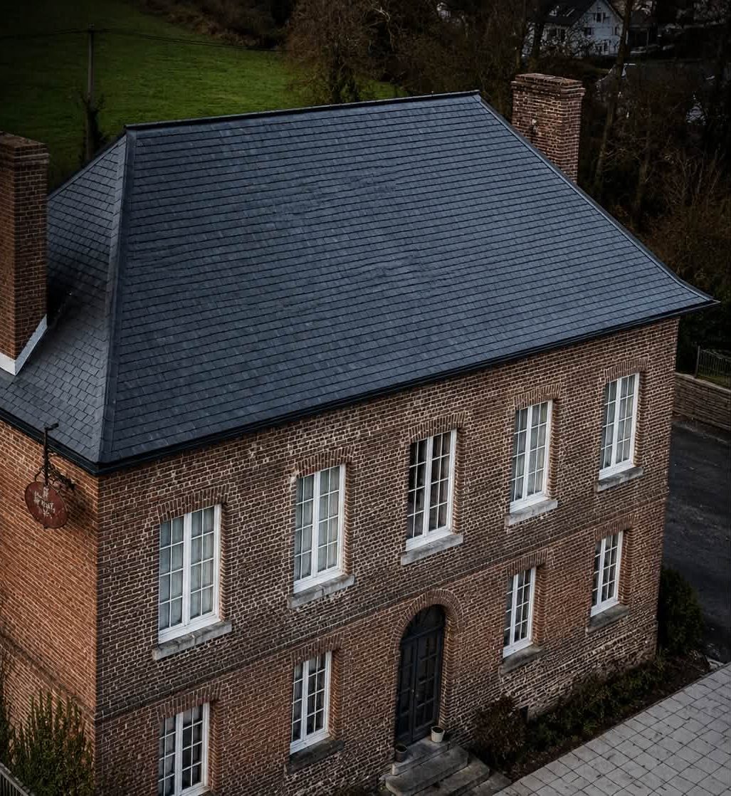 Toiture à quatre pans en ardoise naturelle refaite par Art & Conception sur une maison de maître en brique